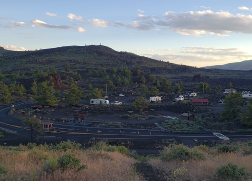 A scenic view of a campground with RVs, surrounded by volcanic rock and greenery under a clear sky.