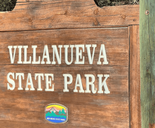 Wooden sign for Villanueva State Park, featuring the park's name and logo.