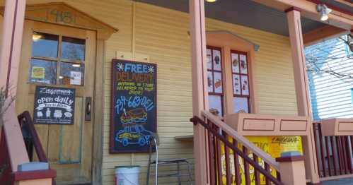 Exterior of a colorful storefront with a sign for free delivery and a menu displayed on the wall.
