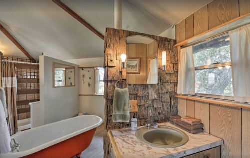 Cozy bathroom featuring a vintage tub, wooden accents, and natural light from windows.