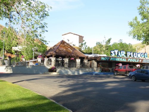 A building with a sign reading "Star Plunge" featuring hot mineral pools, surrounded by trees and flowers.