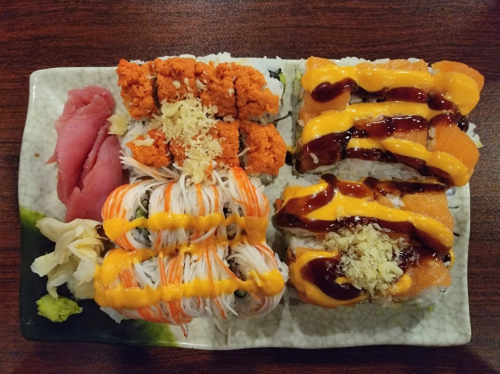 A sushi platter featuring various rolls, tuna slices, and garnishes on a decorative plate.
