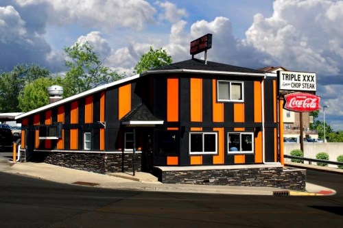 A colorful restaurant with orange and black stripes, featuring a sign for "Triple XXX" and a Coca-Cola advertisement.