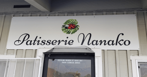 Sign for "Patisserie Nanako" featuring a ladybug and leaf design, mounted on a building exterior.