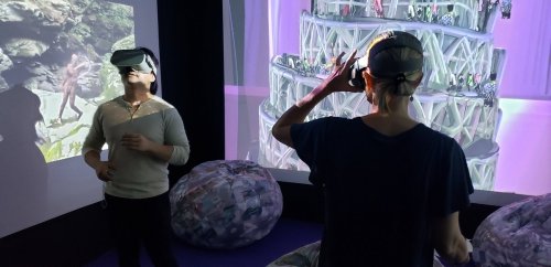 Two people wearing VR headsets in a colorful, immersive environment with projected visuals.