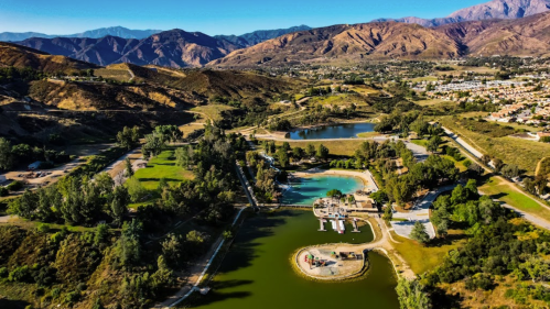 Aerial view of a scenic landscape featuring lakes, greenery, and mountains in the background.