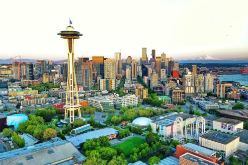 Aerial view of Seattle featuring the Space Needle, city skyline, and lush green parks under a clear sky.