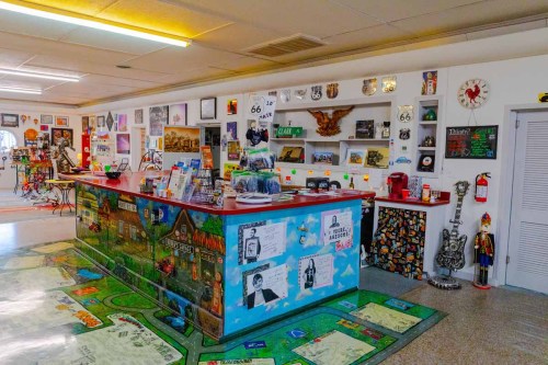 A colorful gift shop interior with a decorated counter, vintage memorabilia, and Route 66-themed decor on the walls.