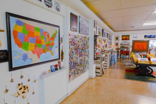 A colorful map of the USA hangs on a wall, surrounded by various artworks and a collection of magnets and souvenirs.