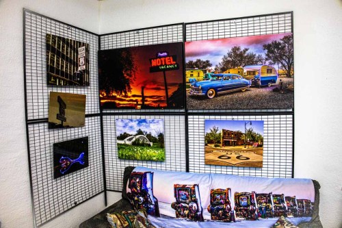 A wall display featuring various colorful photographs and art pieces, with a couch in front.