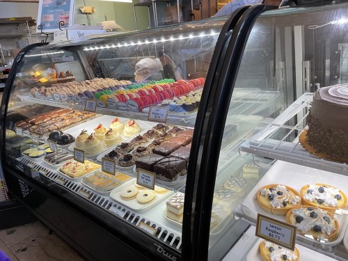 A display case filled with various desserts, including cakes, pastries, and colorful macarons.