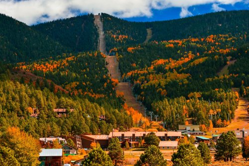 A scenic view of a mountain with autumn foliage, overlooking a small town nestled in the valley below.