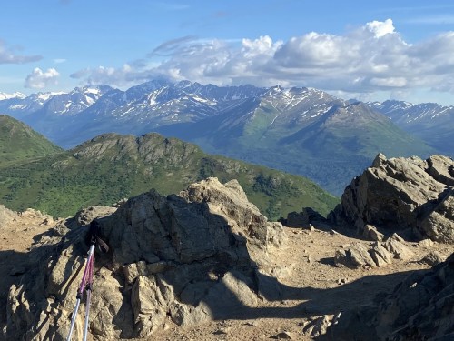 A scenic mountain view with rocky terrain and snow-capped peaks under a blue sky with scattered clouds.