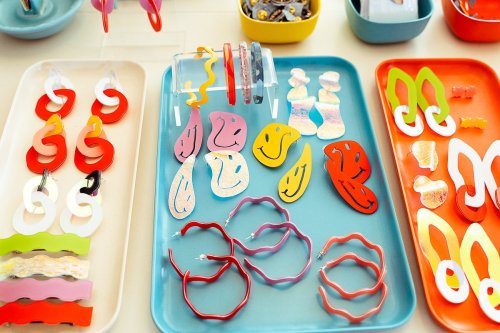 Colorful assortment of playful earrings displayed on trays, featuring various shapes and designs in vibrant hues.