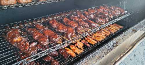 A smoker filled with various meats, including ribs and chicken, all glazed with a rich barbecue sauce.