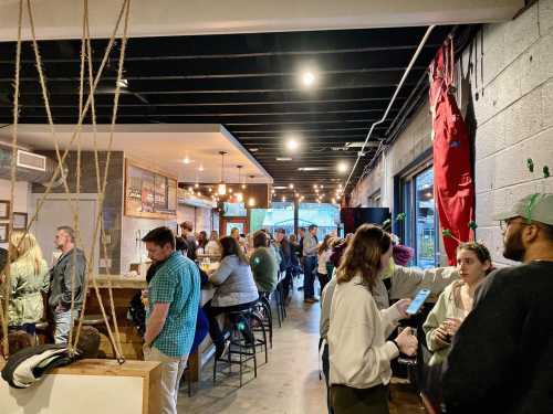 A lively bar scene with people socializing, seated at tables, and standing in a well-lit, modern space.