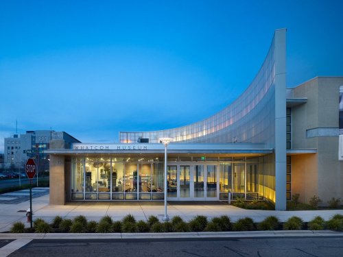 Exterior view of the Whatcom Museum at dusk, featuring modern architecture and large glass windows.