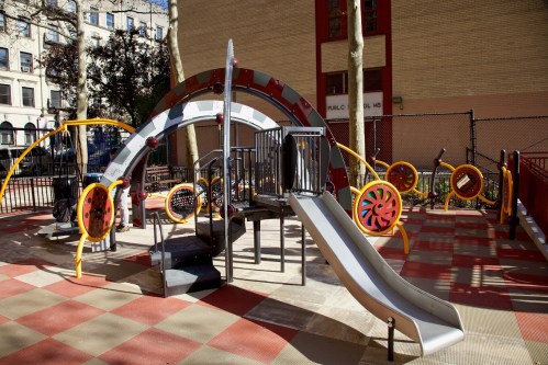 Colorful playground equipment featuring a slide, climbing structures, and interactive elements on a sunny day.