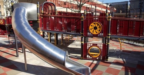 A shiny metal slide on a colorful playground structure with red and yellow accents.