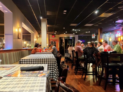 A cozy restaurant interior with checkered tables, dim lighting, and diners enjoying meals and conversations.