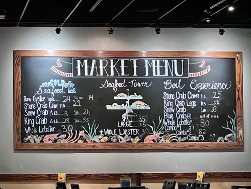 Chalkboard menu displaying seafood options, including prices for oysters, crab, and lobster dishes.