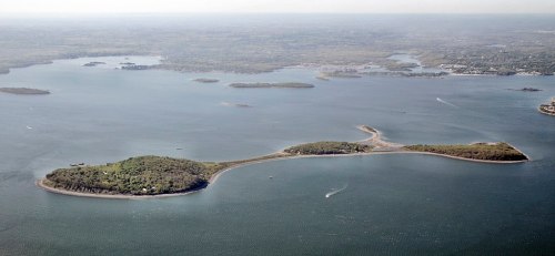 Aerial view of a large, green island surrounded by water, with smaller islands visible in the distance.