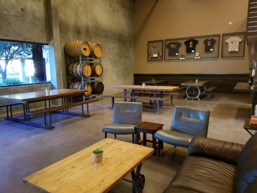 A spacious, modern interior with wooden tables, leather seating, and wine barrels, featuring a relaxed atmosphere.