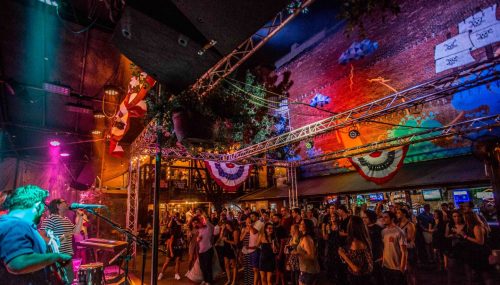 A lively outdoor concert scene with a band performing, colorful lights, and a crowd enjoying the music.