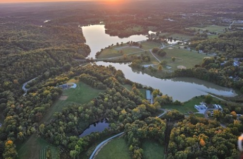 Aerial view of a serene landscape with a winding river, lush greenery, and a sunset in the background.