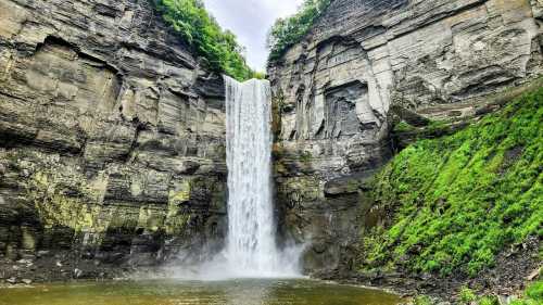 A stunning waterfall cascading down rocky cliffs into a serene pool, surrounded by lush greenery.