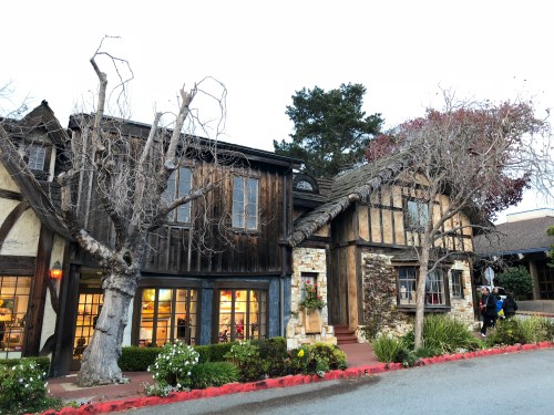 A charming, rustic building with wooden and stone elements, surrounded by trees and flowers, in a serene setting.