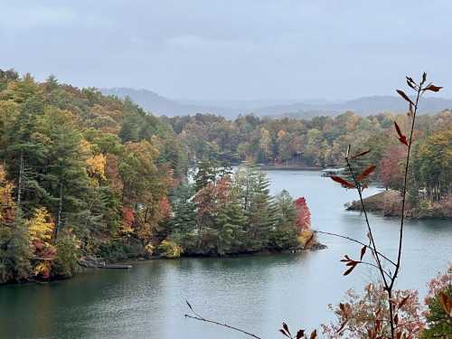 A serene lake surrounded by colorful autumn trees under a cloudy sky.