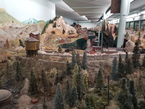 A detailed model train landscape featuring mountains, trees, and miniature buildings along a railway track.