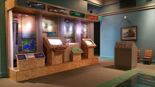 Exhibit display with informational panels and interactive screens in a museum setting.