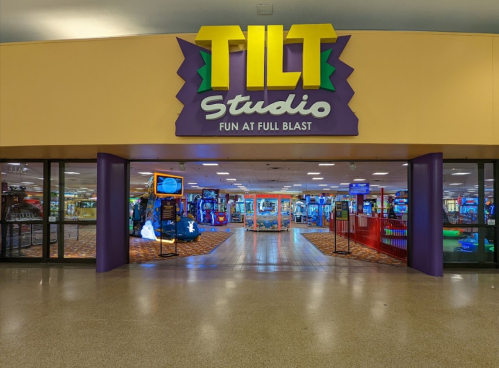 Entrance to TILT Studio, featuring colorful signage and arcade games visible in the background.