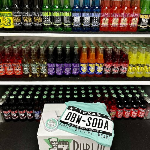 A colorful display of Dublin Bottling Works sodas on shelves, with a box and t-shirt in front.