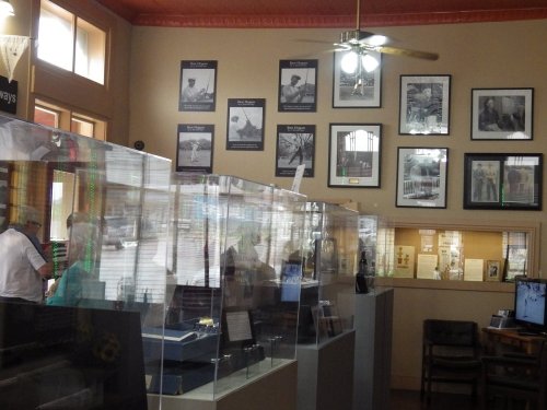 Interior of a museum featuring display cases and framed black-and-white photographs on the walls.