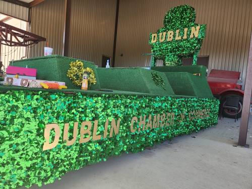 A green float decorated with shamrocks and the words "Dublin Chamber of Commerce" inside a barn.