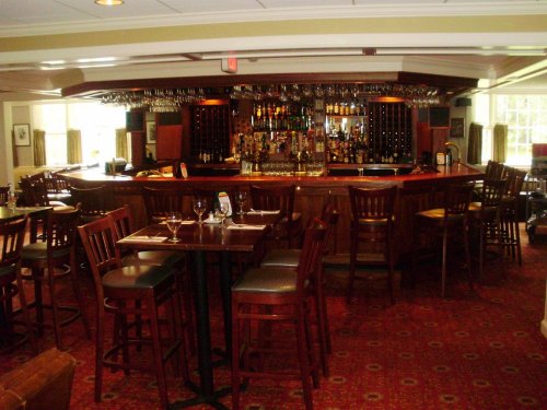 A cozy restaurant bar with wooden furniture, a well-stocked bar, and a warm, inviting atmosphere.