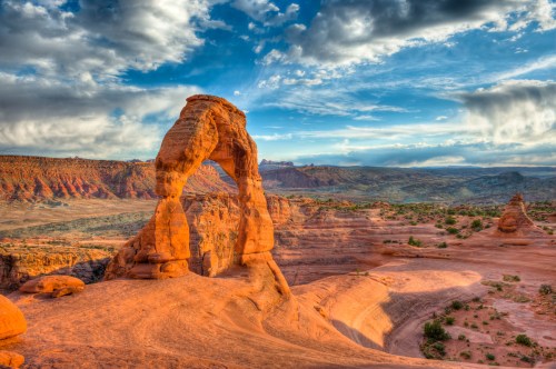 A stunning view of Delicate Arch in Arches National Park, surrounded by red rock formations and a blue sky.