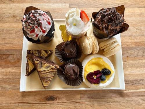 A platter of assorted desserts including cupcakes, macarons, brownies, and a tart with fruit and chocolate.
