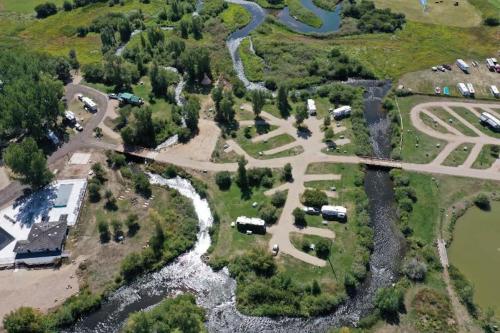 Aerial view of a park with winding streams, green areas, and a campground with several RVs and a building.