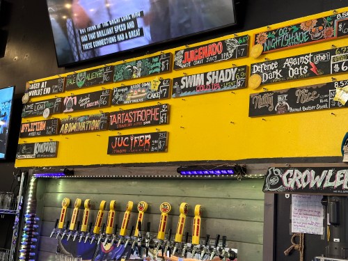 A colorful menu board displaying various craft beers and their descriptions at a bar.