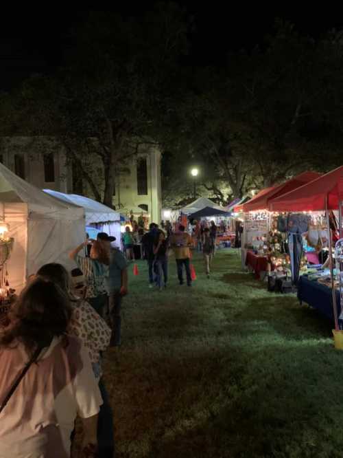 A nighttime market scene with people walking between vendor tents, surrounded by trees and soft lighting.