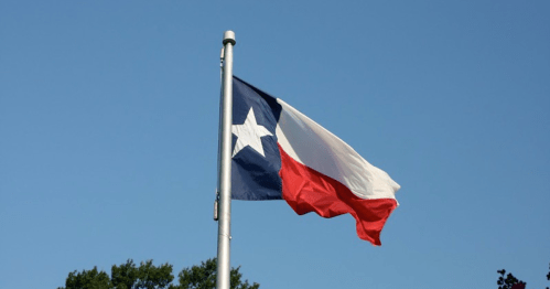 Texas state flag waving against a clear blue sky.