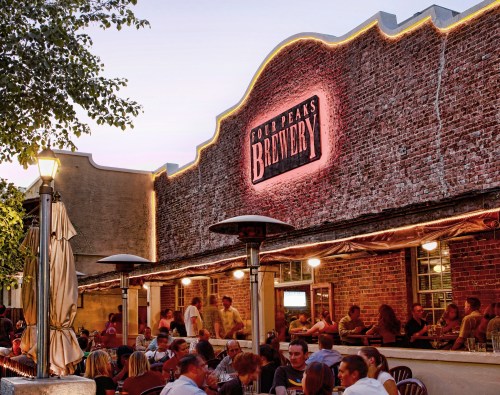 Outdoor seating area of Four Peaks Brewery, with patrons enjoying drinks and a warm evening atmosphere.