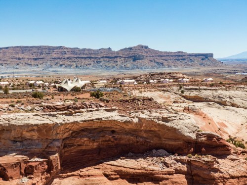 A panoramic view of a desert landscape featuring unique rock formations and modern architecture against a clear blue sky.