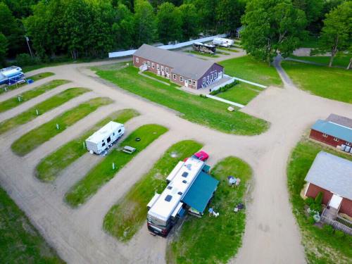Aerial view of a campground with RVs parked in curved rows and a main building surrounded by greenery.