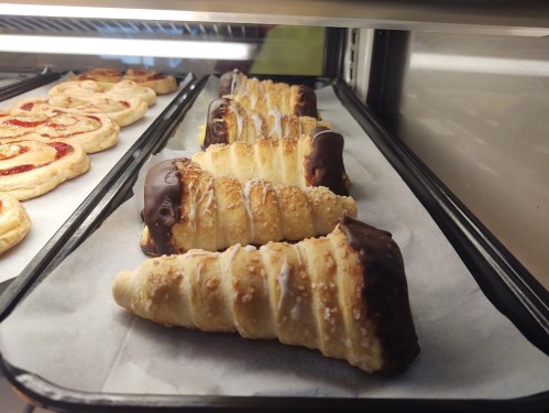 A display of pastry cones coated in chocolate and sprinkled with nuts, arranged on a tray.
