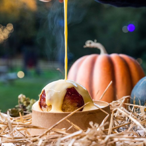 A warm dessert with gooey sauce drizzling over it, surrounded by pumpkins and autumn decor.